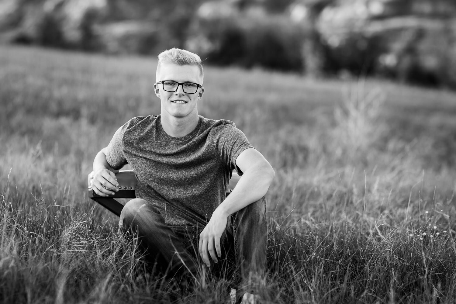 Black and white of senior boy sitting in a field
