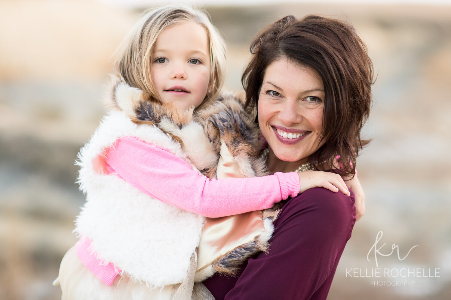 mom holding daughter in pink and maroon clothing