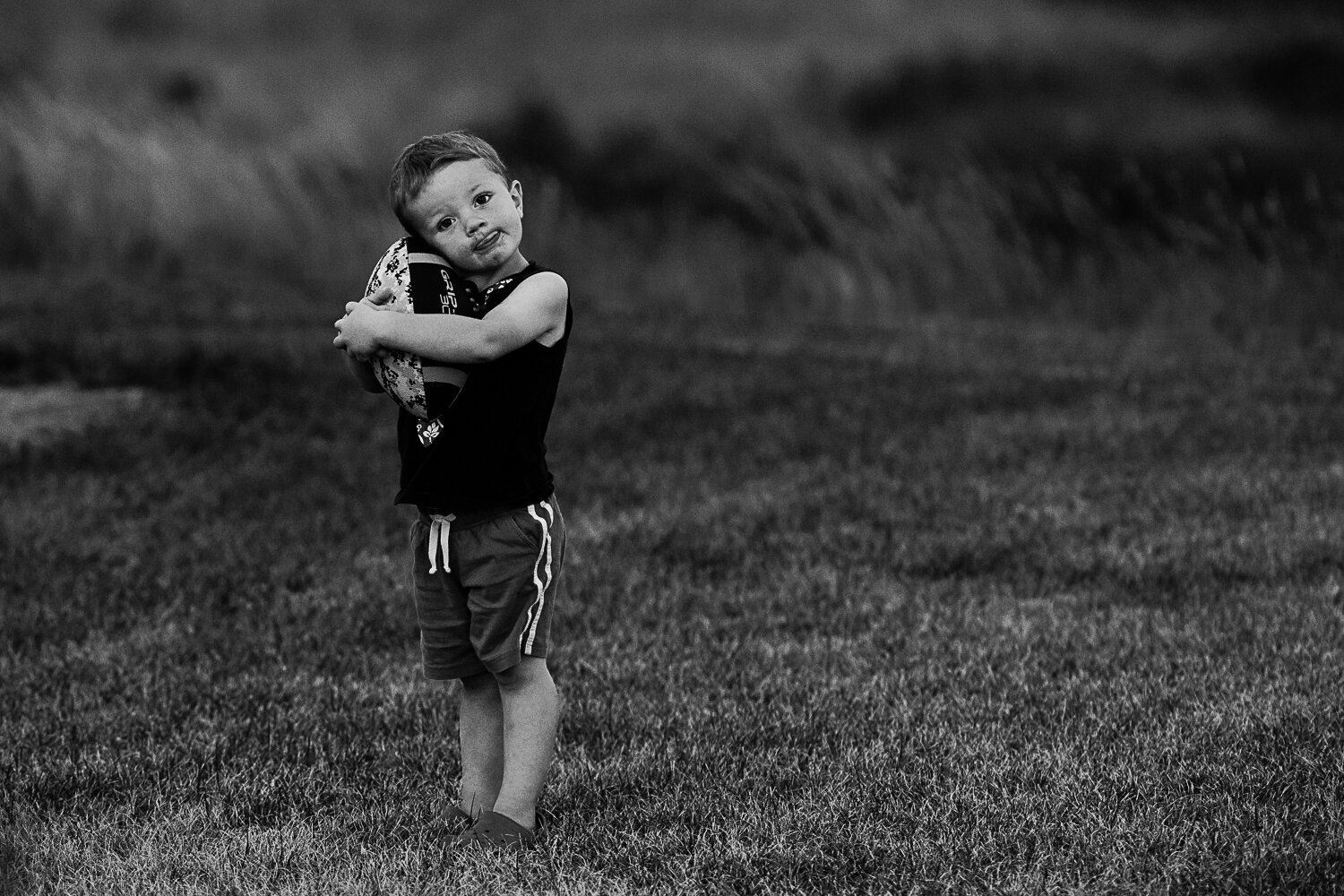 toddler hugging football black and white photo- Williston documentary photography