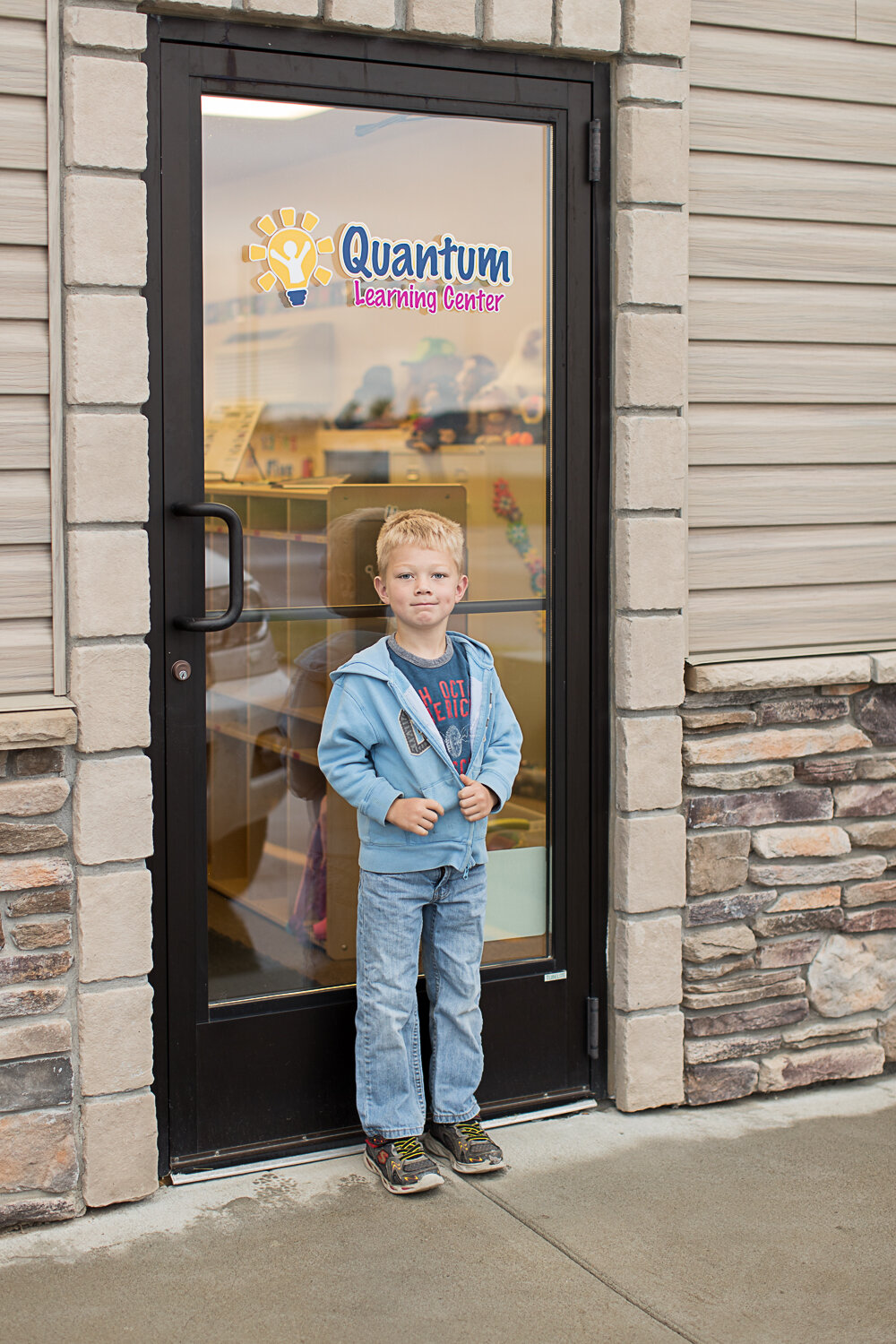 little boy standing in front of school door- Williston children photography