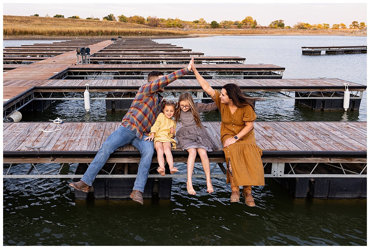A mother and father high-five on a boat dock with their children