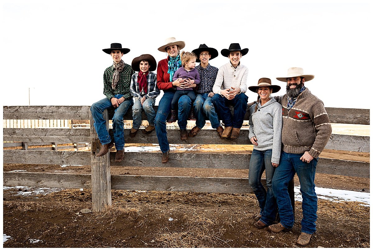 The Hartfeld family pose on a fence at the Richard Angus Ranch in their jeans, boots, and hats during a photoshoot for Farm & Ranch Magazine by Kellie Rochelle Photography.