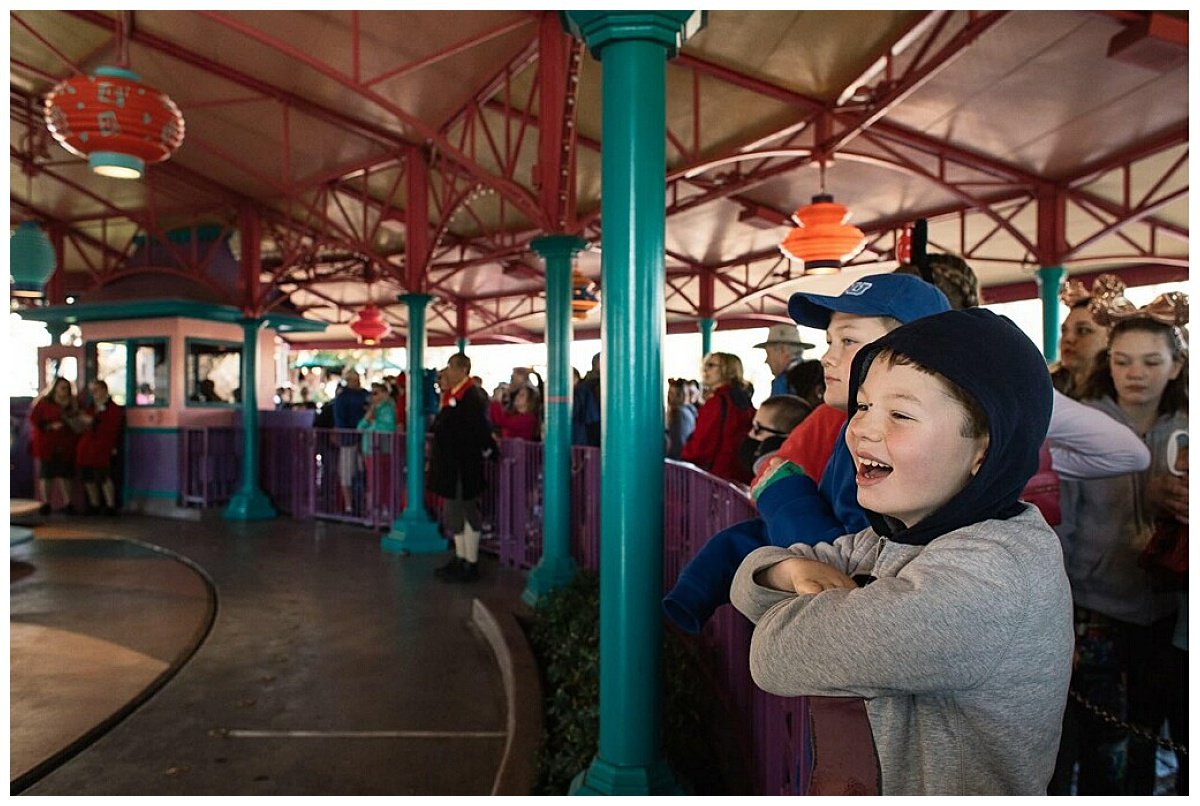 Two young boys smile as they wait their turn on an attraction at Disney World.