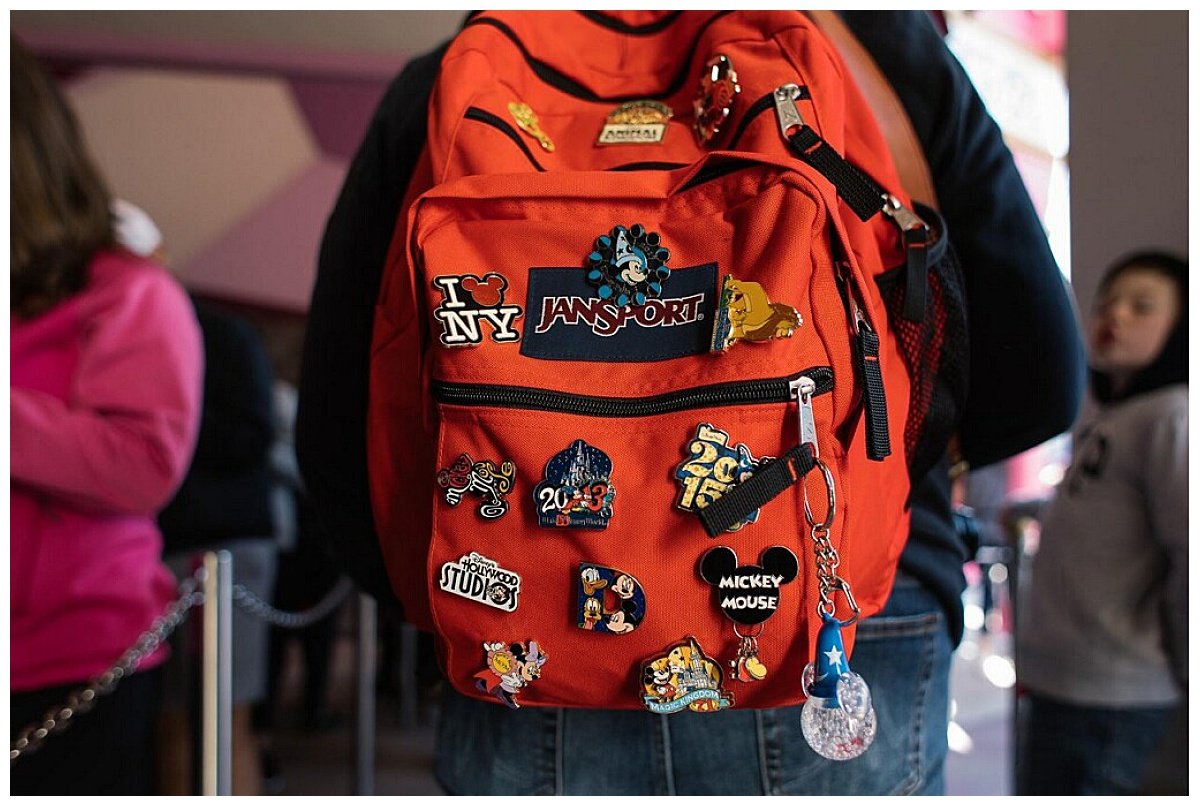 A photo of an orange Jansport backpack covered in Disney-themed pins during a family trip to Disney World in Florida.