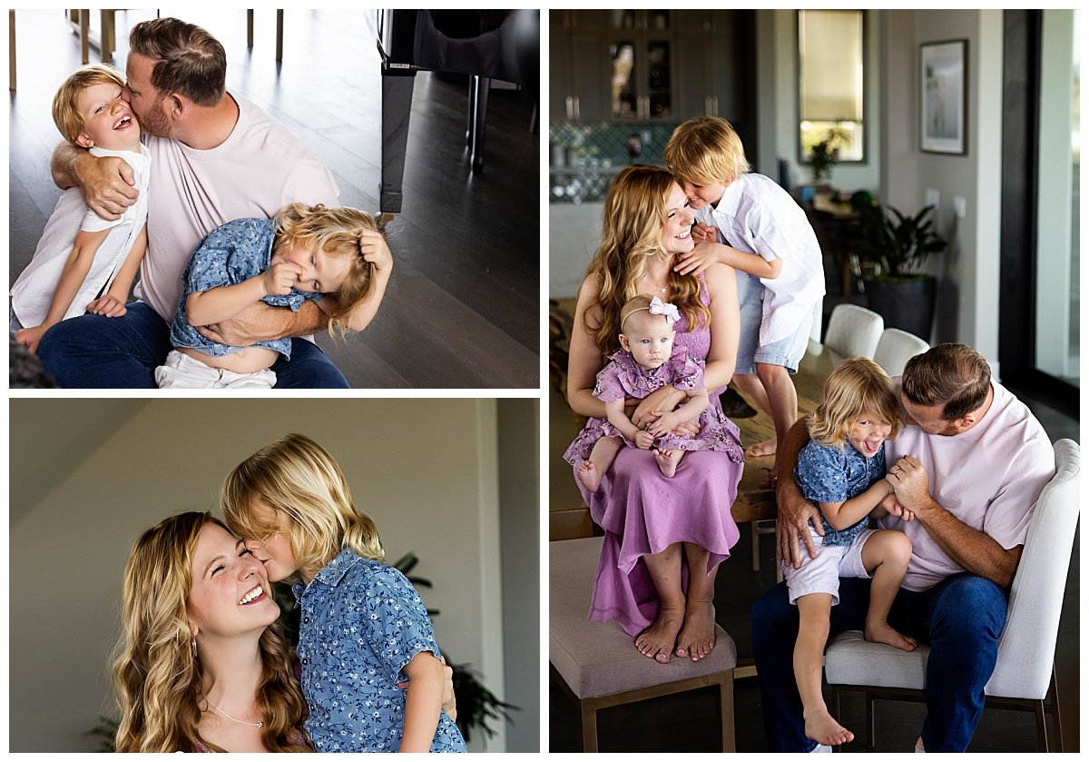 A father kisses his two blonde sons while their blonde mother in a lavender dress snuggles and plays with their infant daughter during an in-home family photo session.