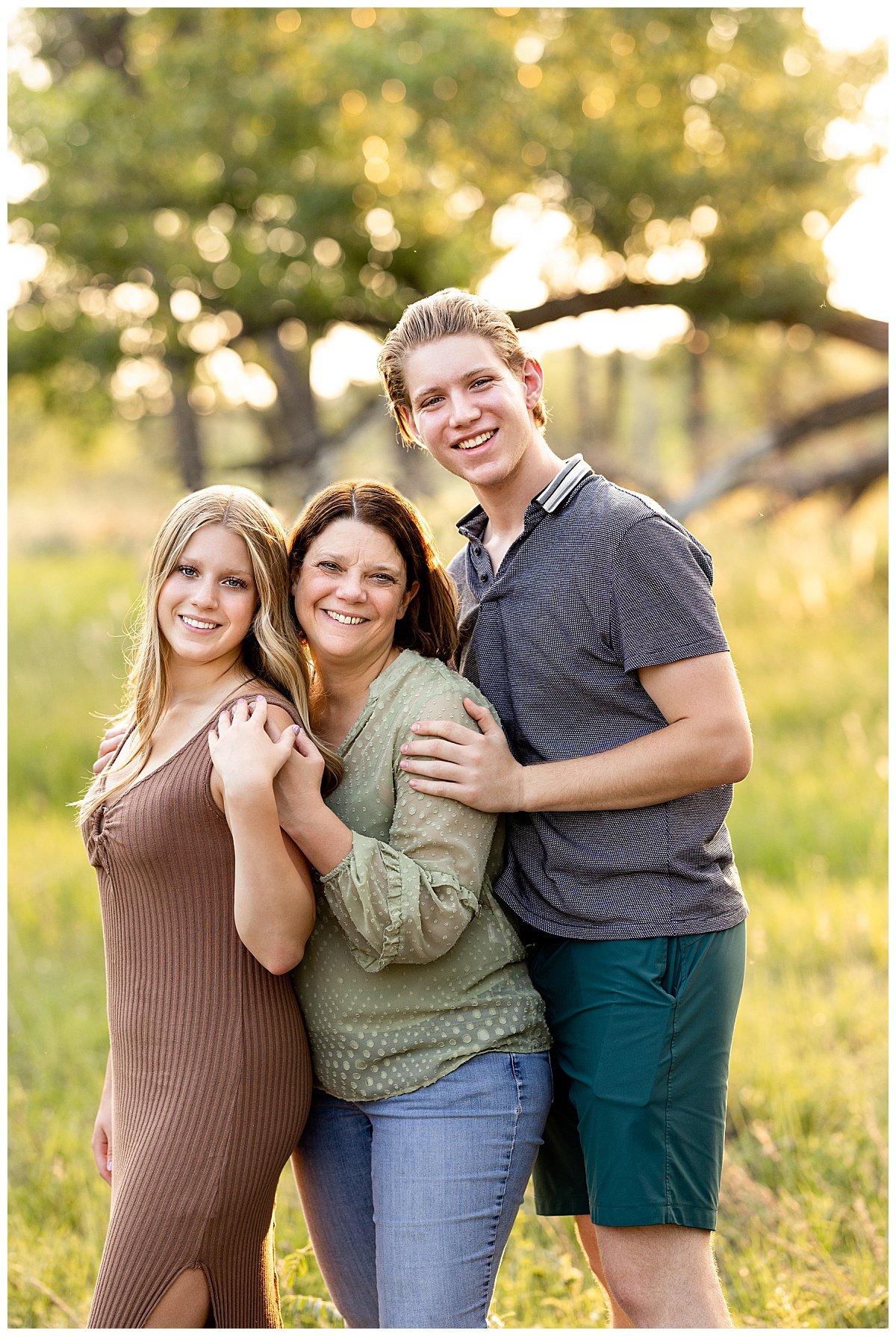 A senior girl poses with her mother and brother during a golden hour session