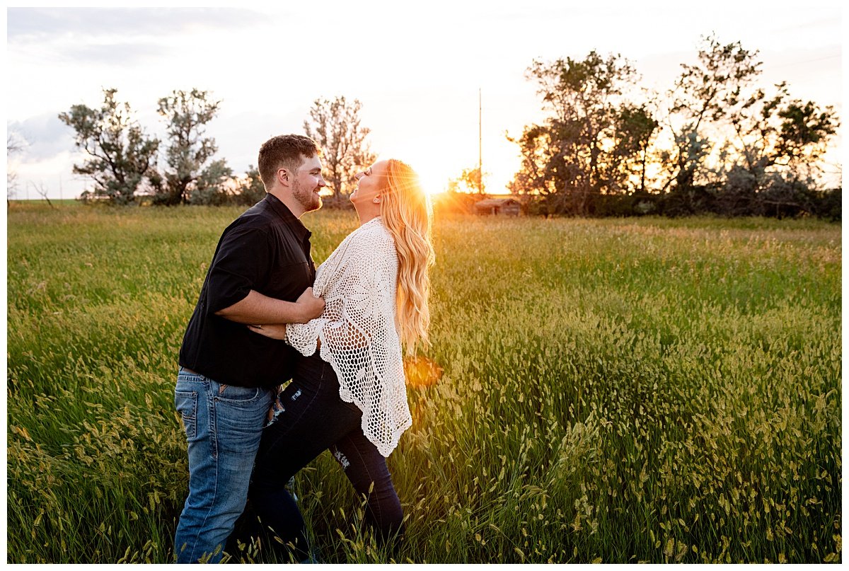 A newly engaged North Dakota couple share a kiss at golden hour during an engagement photoshoot on their farm.