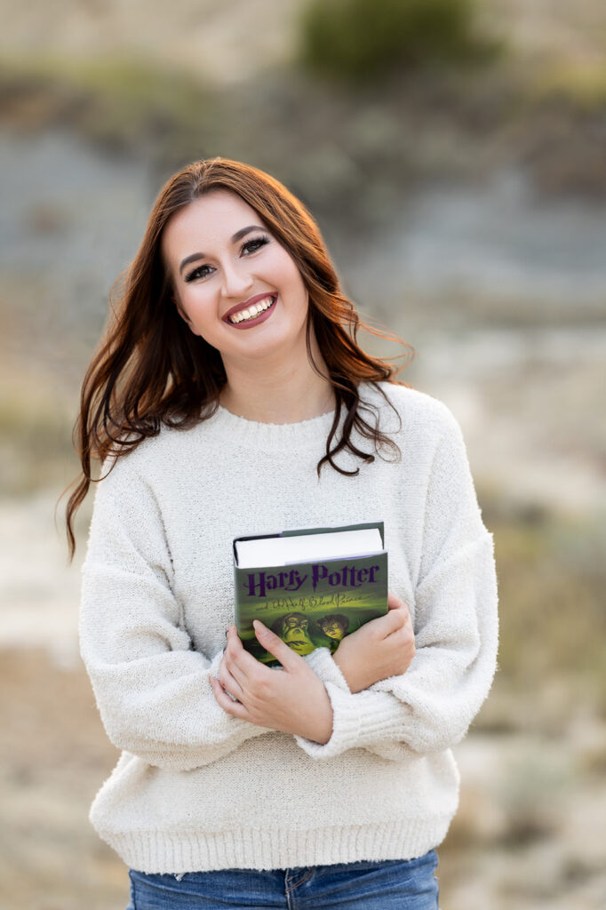 Pictured is a class of 2024 senior holding her  copy of Harry Potter for her senior photos with Williston, ND based photographer, Kellie Rochelle Photography. 