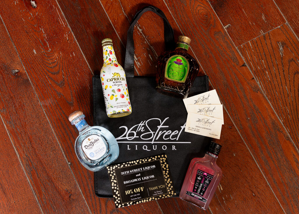 A selection of the drinks available at 26th Street Liquor is displayed atop a tote bag with the store's logo in Williston, ND.