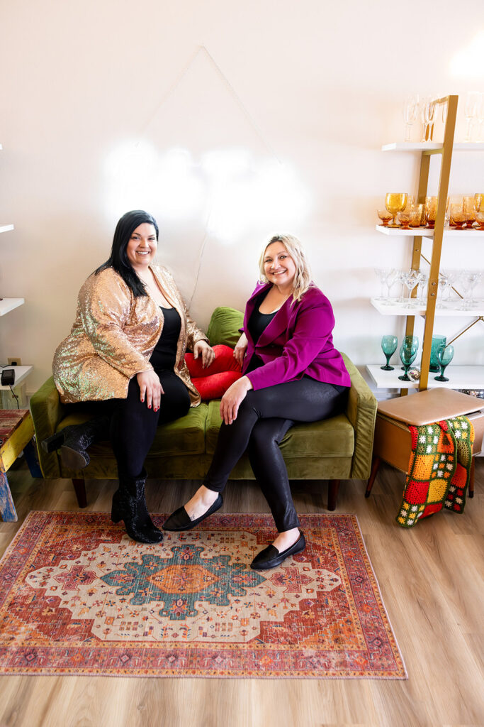 North Dakota wedding planners, House of Style, are pictured seated on an olive green couch in the lobby of their Williston, ND building. 