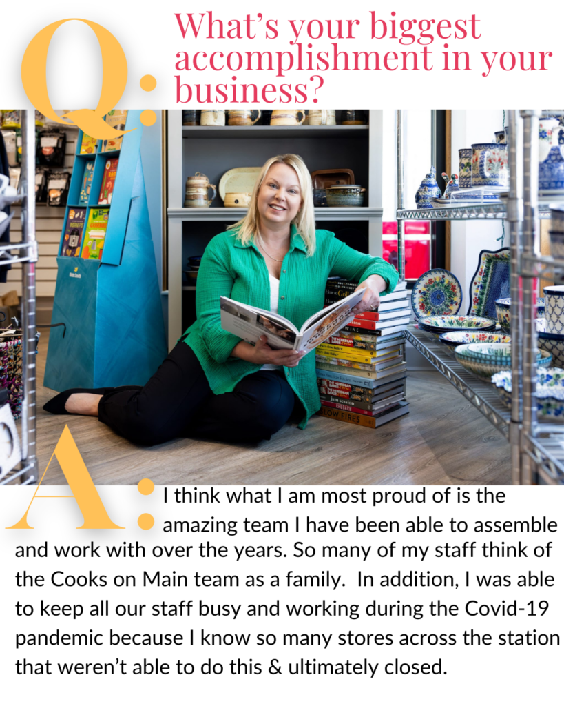 Angela Skogen, owner of Cooks on Main, is photographed seated on the floor of her Williston, ND kitchen store wearing a green linen shirt surrounded by decorative dishes & a stack of cookbooks during a branding photoshoot with Kellie Rochelle Photography.