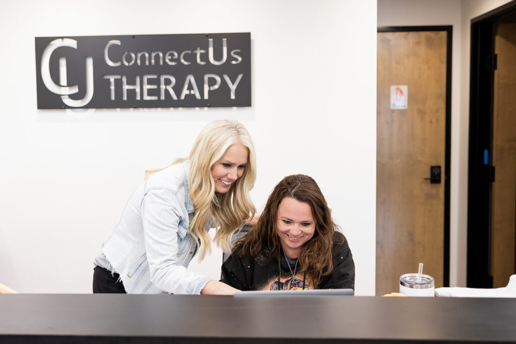 ConnectUs Therapy founder, Katie Shannon, is photographed with her staff in front of a sign in the lobby of the Williston mental health practice during a brand session with Kellie Rochelle Photography.