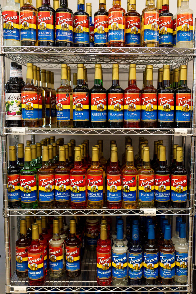 A shelving display of Turoni's syrups are shown in Williston, ND storefront, Cooks on Main, is shown as part of a business branding session by Kellie Rochelle Photography.