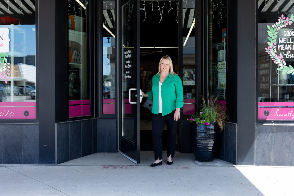 Angela Skogen, owner of Williston, ND kitchenware store, Cooks on Main, stands in the entry of the storefront during a brand shoot with Kellie Rochelle Photography.