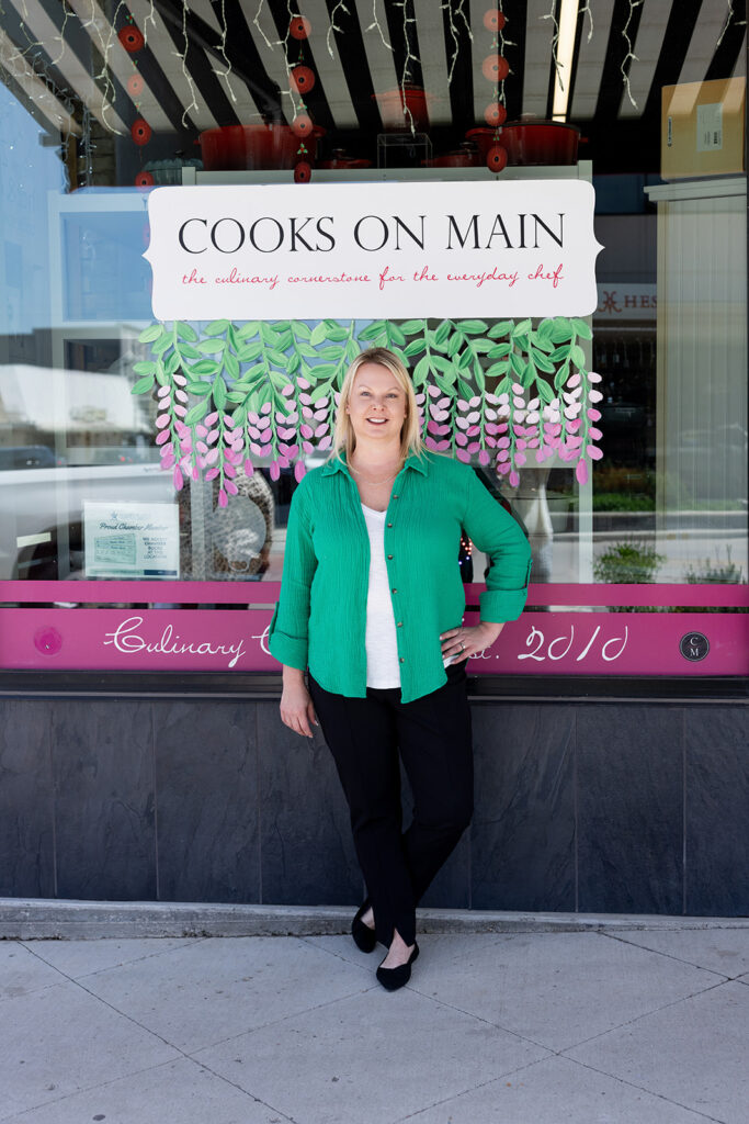 Angela Skogen, owner of Williston, ND kitchenware store, Cooks on Main, stands in the entry of the storefront during a brand shoot with Kellie Rochelle Photography.