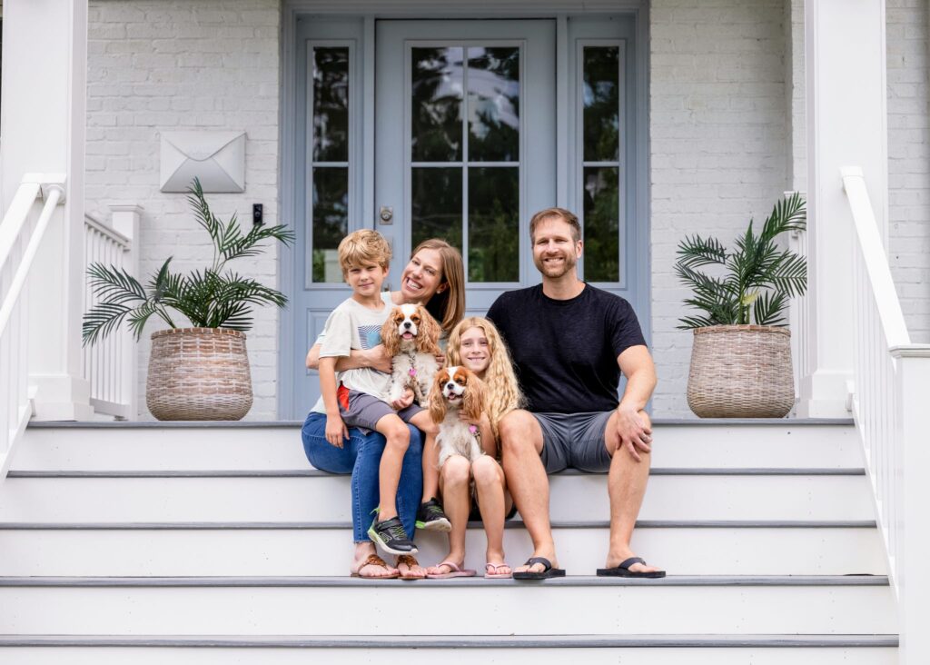 A D.C. family of four poses with their two small dogs on the front porch of their Washington D.C. home during a family videography shoot with Backing Small Businesses Grant recipient, Kellie Rochelle Photography.