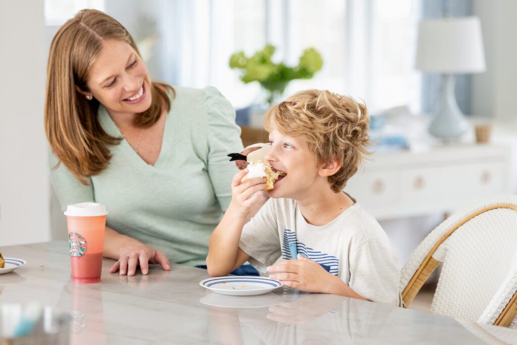 A mother & son smile as they enjoy a homemade cinnamon roll baked during a family videography shoot with North Dakota family photographer & videographer, Kellie Rochelle Photography.