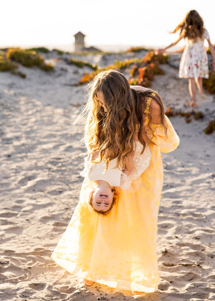 A mother & her daughters laugh on a California beach during a photography mentorship photoshoot