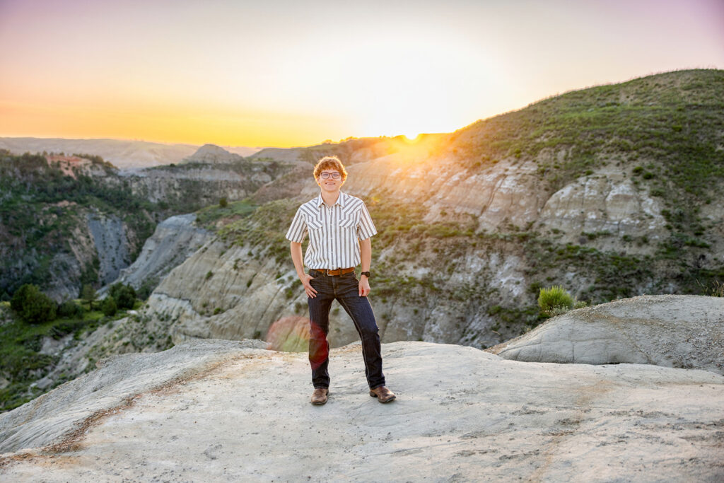 Hunter in jeans and cowboy boots with the sunset glowing behind him at the North Unit.