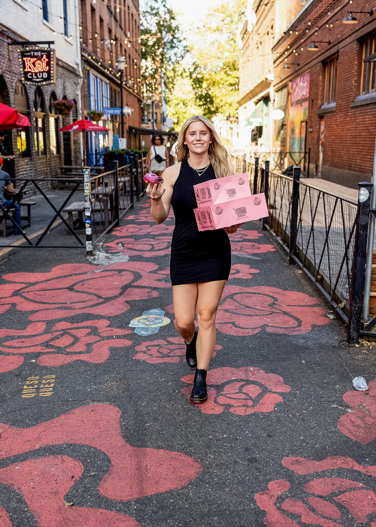 Kaitlyn holding a Voodoo Doughnut in Portland during her senior photo session.
