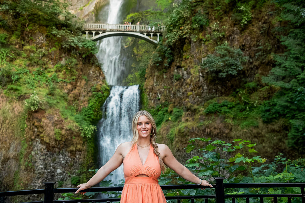 Kaitlyn posing in front of Multnomah Falls, a stunning backdrop for her senior travel photography session