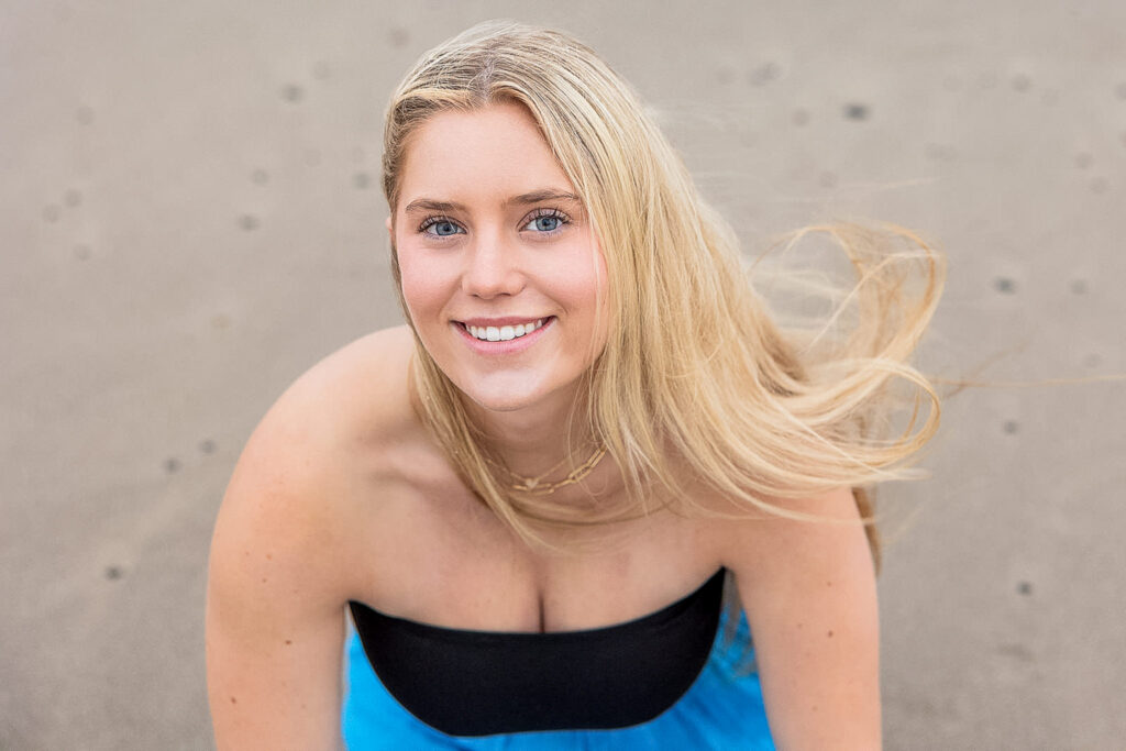 Kaitlyn standing on the misty shores of Twin Rocks Beach at sunrise for her senior travel photography session.