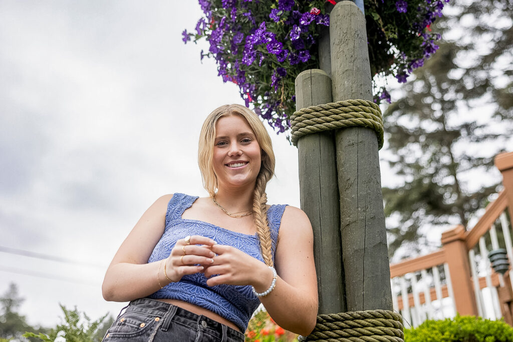 Kaitlyn posing by the flowers in Seaside, Oregon, during her senior travel session
