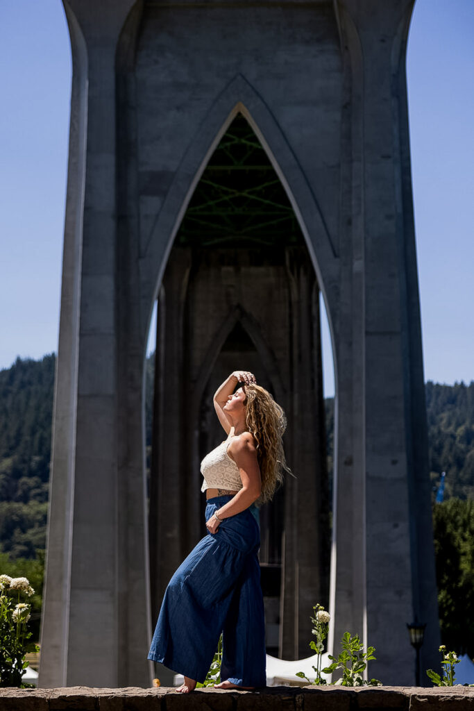 Kaitlyn posing under the iconic arches of Cathedral Park in Portland during her senior travel photography session.