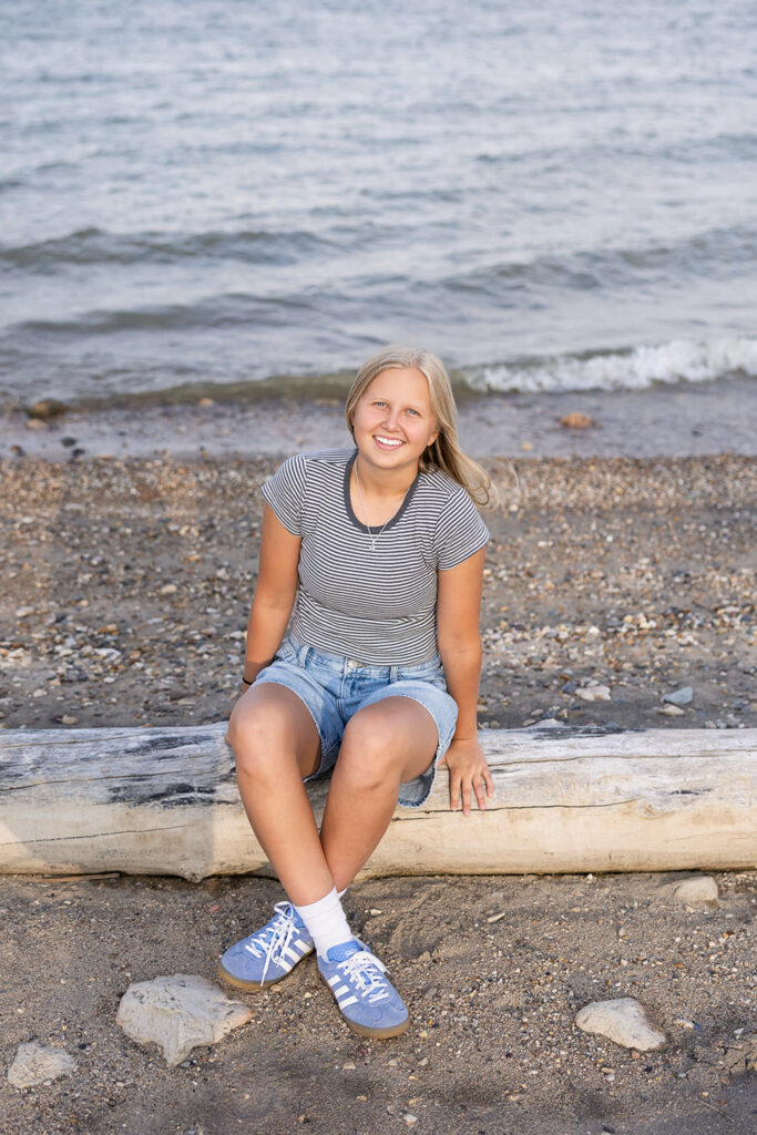 Lake Sakakawea senior photos at sunset – A high school senior sitting by the water at Lake Sakakawea with golden-hour lighting.