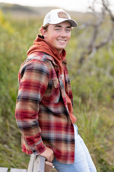 senior Sunday boy in plaid leaning against a bench 