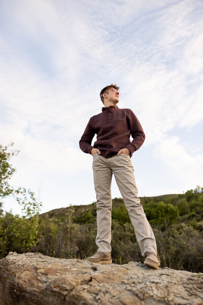 Senior Sunday Boy standing on a rock with trees behind him 