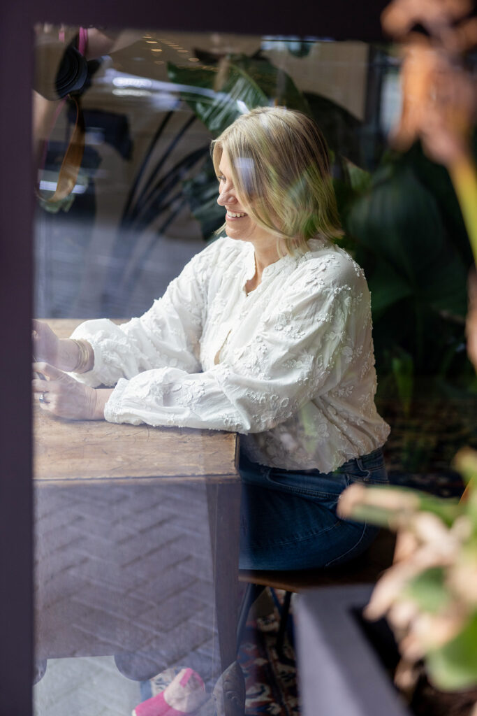 A photographer is photographed through the glass of an Austin TX business during a headshot session with Kellie Rochelle Photography, a ND based destination photographer