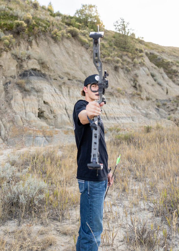 Hudson posing with his bow in the Badlands-inspired landscape