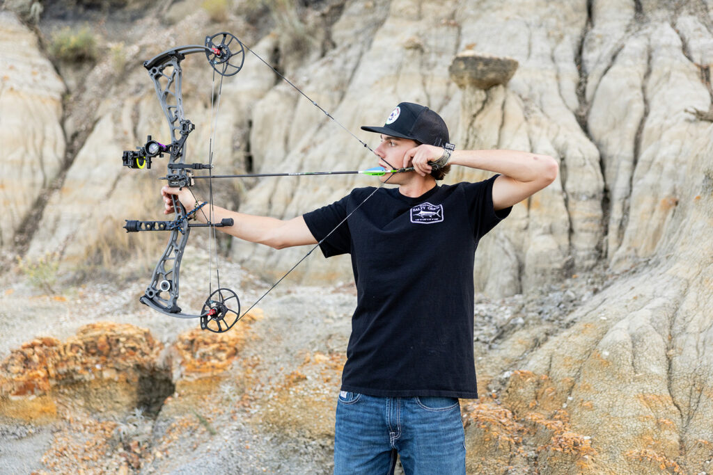 Hudson posing with his bow in the Badlands-inspired landscape