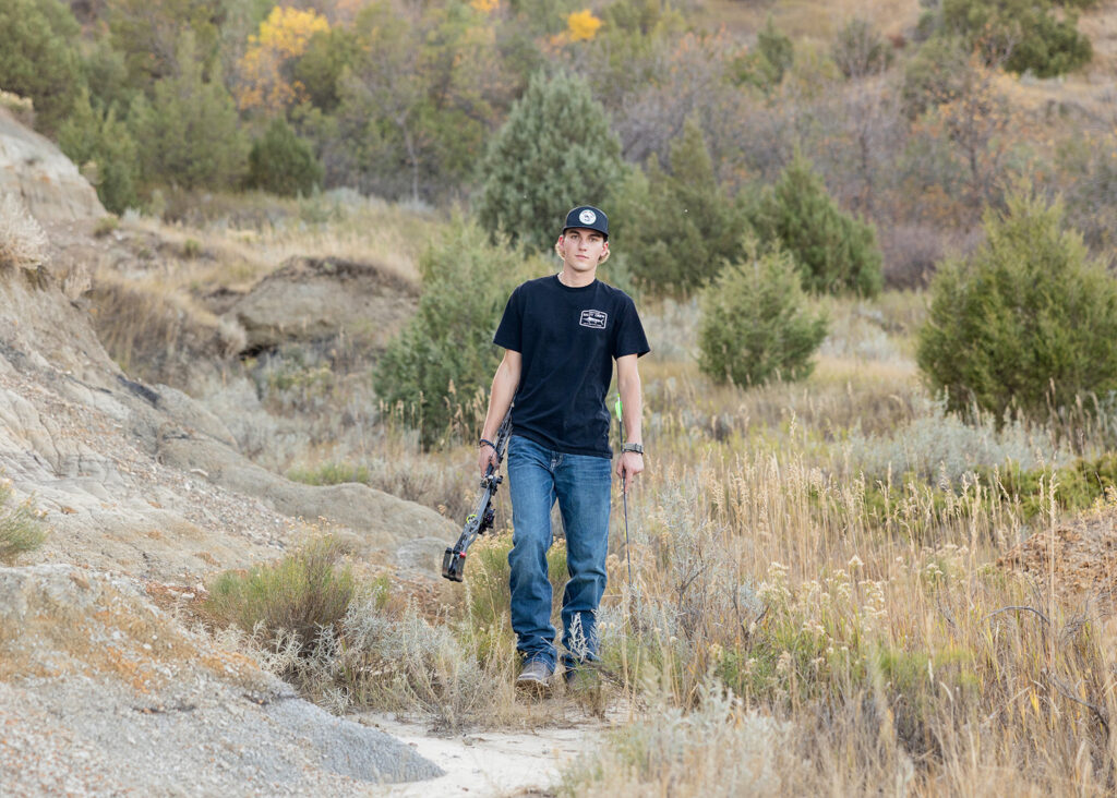 Hudson posing with his bow in the Badlands-inspired landscape