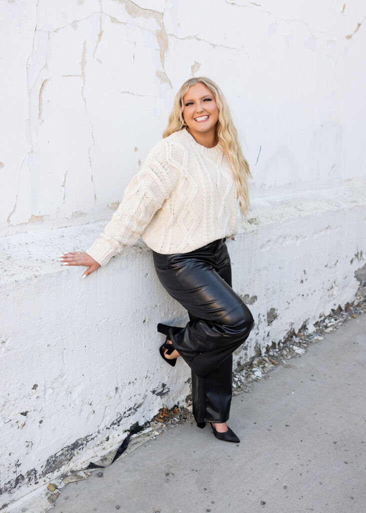 Senior girl leaning against white brick wall 