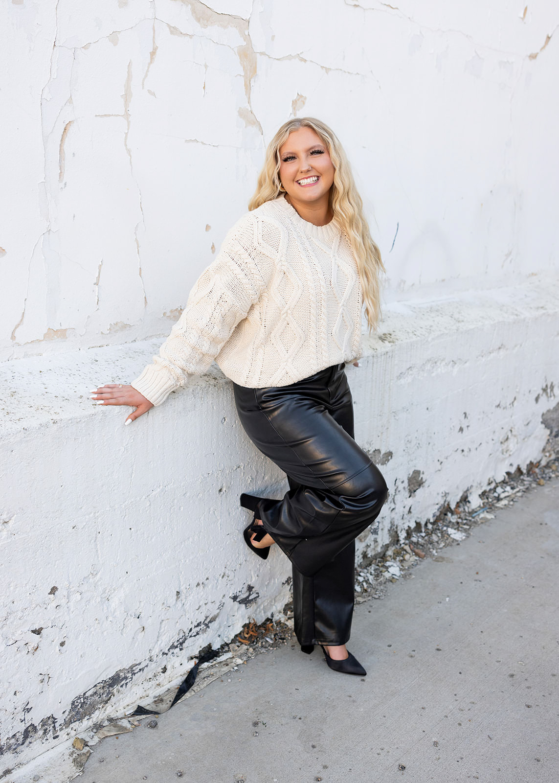 Senior girl leaning against white brick wall