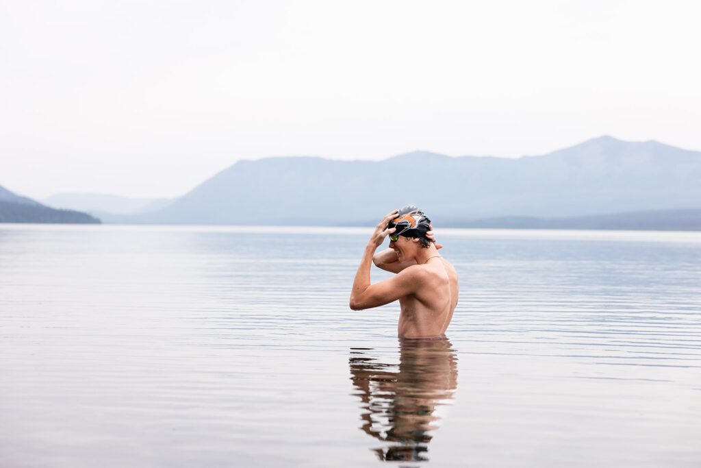 A senior boy swims in Lake McDonald at Glacier National Park during senior photos in MOntana