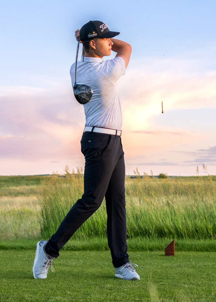 A North Dakota high school senior poses at sunset with his golf clubs in a session with ND Senior photographer, Kellie Rochelle Photography