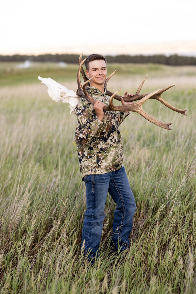 A Williston high school senior poses in a field while wearing camo during a photoshoot with ND Senior photographer, Kellie Rochelle Photography 