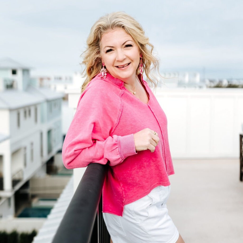 Photographer in a pink sweater smiling outdoors, representing confidence and recovery from creative burnout.