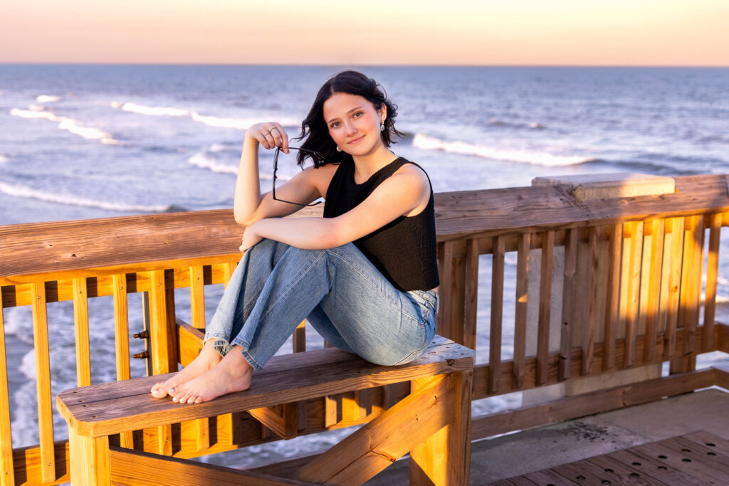 Charleston senior girl sitting on the Folly Beach pier at golden hour
