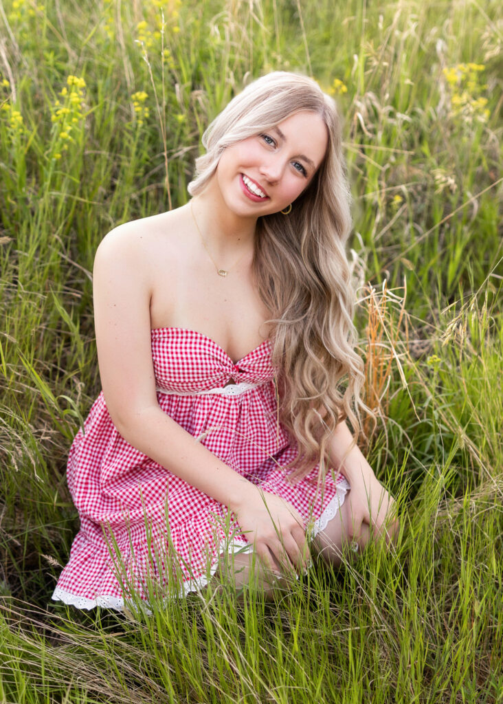 Hailey in red plaid dress and brown cowboy boots in tall grass