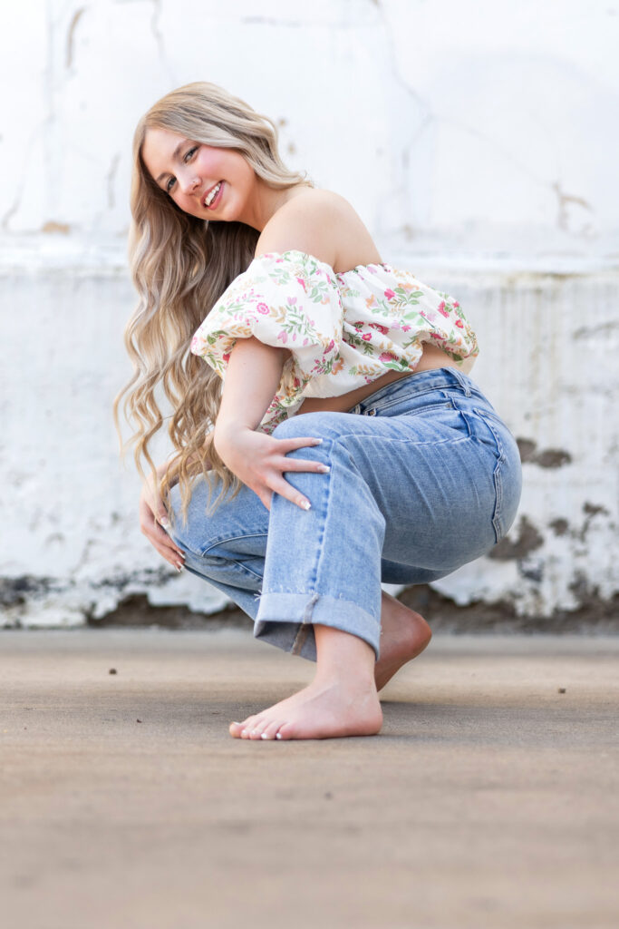 Hailey in floral off-shoulder top near white distressed wall