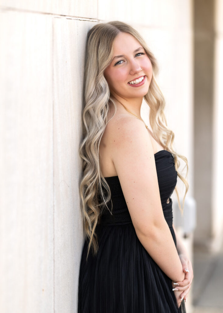 Hailey in black strapless gown in front of marble wall in downtown Williston