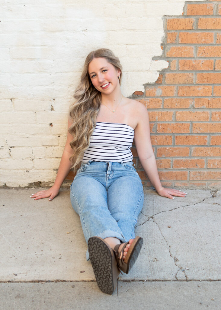 Hailey in striped tube top and jeans in a quiet alleyway with natural light