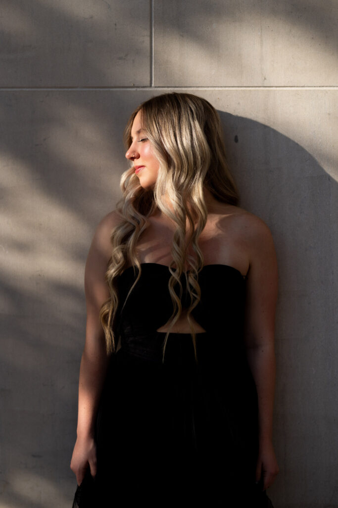 Hailey in black strapless gown in front of marble wall in downtown Williston