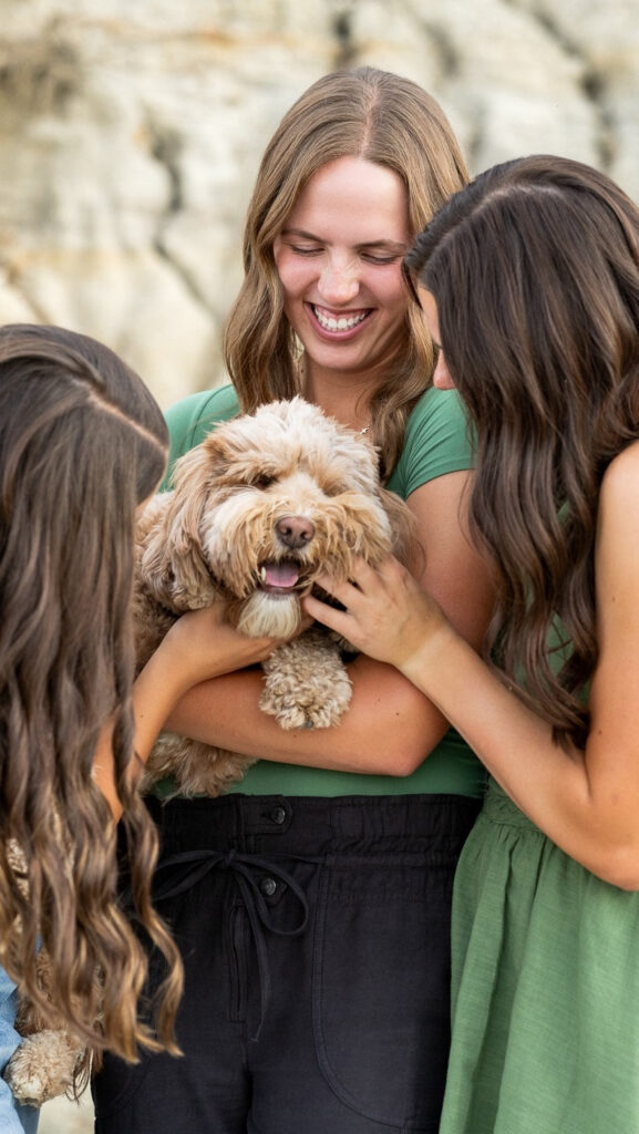 Three women smiling while petting a fluffy dog, a joyful reminder of balance during slow business growth.