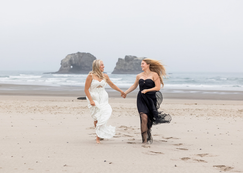 two young women running hand in hand on the beach during a destination shoot
