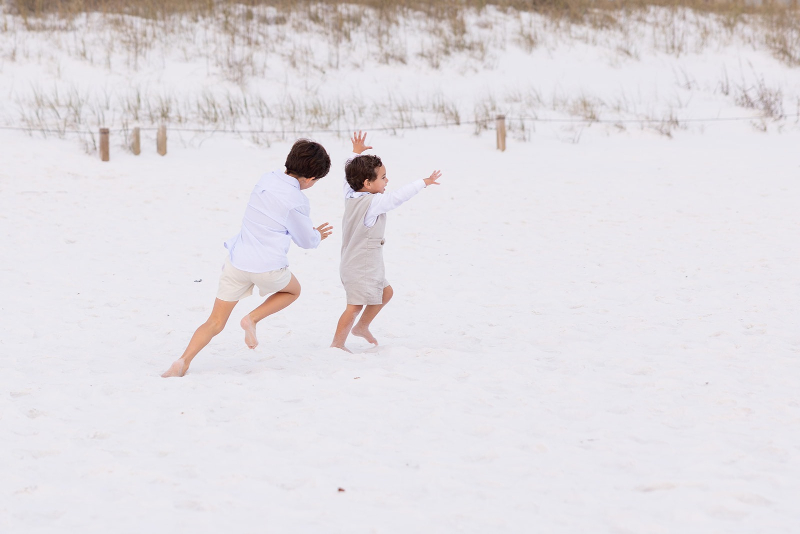 Mother and son playing joyfully in white sand during off-season travel sessions at the beach